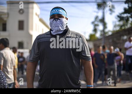 San Salvador, El Salvador. 9th Feb, 2020. Un sostenitore di Nayib Bukele indossa una fascia e facemask nella periferia del Congresso.il presidente Salvadoran Nayib Bukele ha raggiunto il Congresso accompagnato da decine di soldati e ha minacciato i legislatori di approvare un prestito per un piano di sicurezza dopo aver richiesto una sessione di congresso di emergenza.Bukele ha tenuto un rally al di fuori del Congresso Salvadoran, dove una folla ha cantato slogan e minacce contro i legislatori. Credit: Latest Freedman/Zuma Wire/Alamy Live News Foto Stock