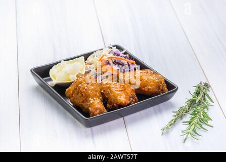 ala di pollo fritto e insalata su tovaglia su tavola di legno bianco in cucina, antipasto menu cibo. Foto Stock