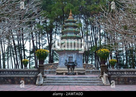 Torre Buddista circondata da Rami di albero Sterile all'interno della Pagoda Thien Mu o Pagoda della Signora Celeste, un tempio storico a Hue, Vietnam Foto Stock
