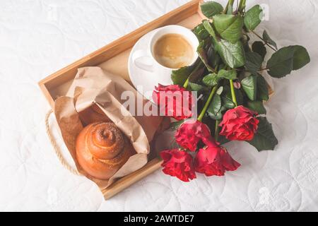 Un vassoio con una tazza di caffè e un panino con un bouquet di rose rosse su  un letto bianco. Regalo per San Valentino Foto stock - Alamy