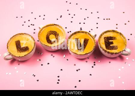 Tazze da caffè di San Valentino concept con amore per la parola sulla superficie frothy su sfondo rosa con piccoli cuori. Concetto di giorno San Valentino minimalista. Foto Stock