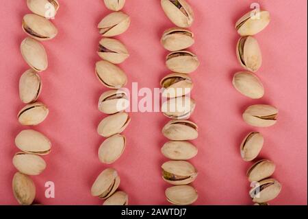 Linea di pistacchio secco su sfondo rosa sopra la vista dall'alto Foto Stock