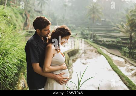 Giovani latino-donna incinta con il marito con incredibile vista di Ubud terrazze di riso. Incinta coppia felice insieme. Foto Stock