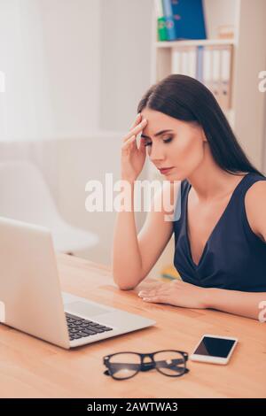 Ritratto di giovane donna d'affari stanco che ha mal di testa in ufficio Foto Stock