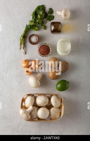 Verdure e spezie su sfondo di cemento chiaro. Concetto di cucina vegetariana. Foto Stock