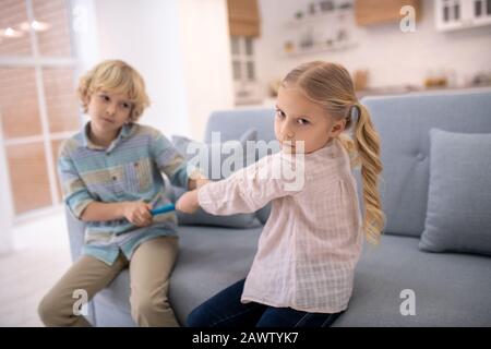 I bambini litigano, cercando di prendere un tablet l'uno dall'altro Foto Stock