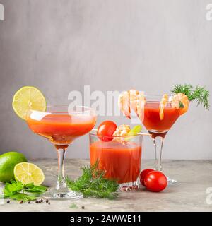 Vari cocktail a base di succo di pomodoro, gamberetti, Maria sanguinosa e gli ingredienti di pomodoro, lime, gamberetti, sedano. Bevande forti in occhiali eleganti Foto Stock