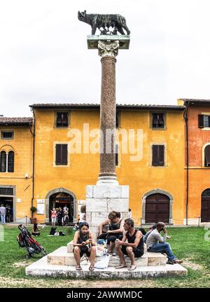 Italy.Pisa.Tuscany.(Toscana).Turisti che si godono una pausa pranzo sotto la statua del lupo Capitolino di Roma. Foto Stock