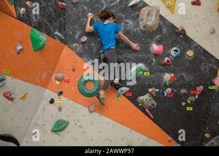 Bambino su un muro di arrampicata , giovane ragazzo Bouldering Foto Stock