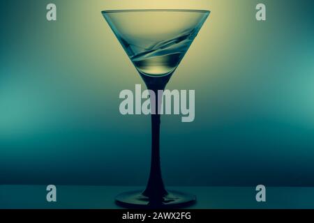 Bicchiere Martini con spruzzi d'acqua su sfondo incandescente. Cocktail trasparente Foto Stock