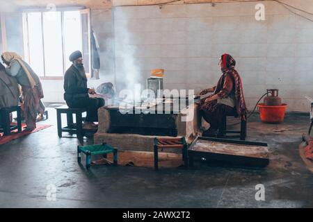 Amritsar India - 8 febbraio 2020: Sikh uomo e donna indiana preparare chapati - pane indiano tradizionale al Tempio d'oro (sri harmandir sahib) Foto Stock