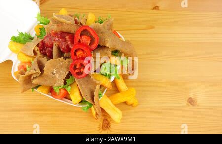Asili chebab carne e patatine con insalata e salsa di peperoncino in un vassoio take away su un fondo di legno Foto Stock
