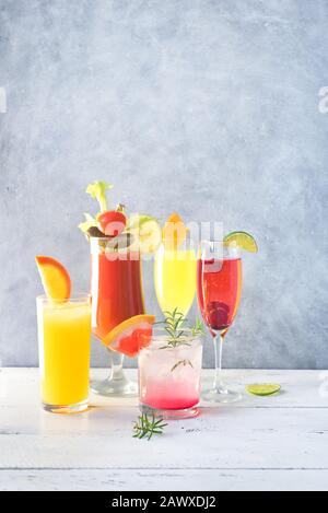 Assortimento Di Cocktail Per Brunch O Colazione. Sanguinante Mary, bevande Mimosa e vari alcolici agrumi cocktail rinfrescanti su tavola grigia, spazio copia. Foto Stock