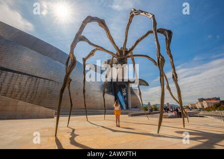 Donna si trova sotto una scultura di un ragno gigante al Museo Guggenheim, Bilbao, Paesi Baschi, Spagna, Penisola Iberica, Europa occidentale Foto Stock