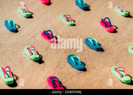 Modello di sandali colorati sulla spiaggia o di tenaglie su una spiaggia di sabbia. Foto Stock
