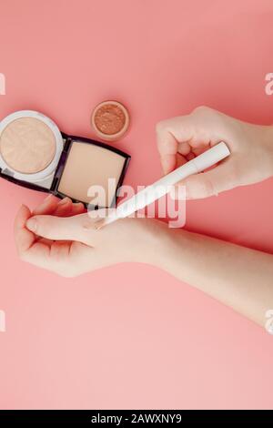 Donna di bellezza blogger mani tenuta bottiglia e tubo spa professionale hi-end cosmetici su sfondo rosa, concetto di minimalismo, calde tonalità accoglienti e. Foto Stock