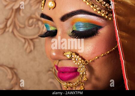 Ritratto di una sposa indiana indossando sari rossi con gioielli pesanti. Profilo laterale della faccia in primo piano Foto Stock