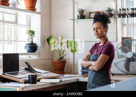 Giovane artigiano in piedi da un banco di lavoro nel suo studio di incorniciatura Foto Stock