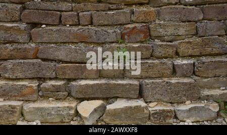 muretto abbandonato e rotto muro di roccia, vecchia parete di roccia per lo sfondo Foto Stock
