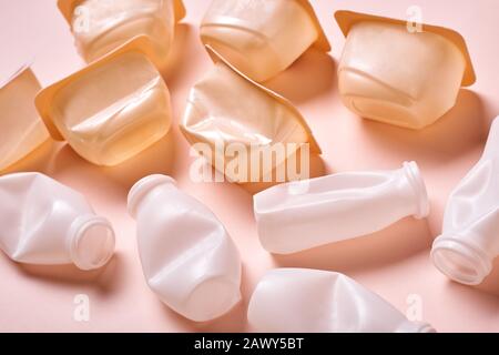 Shot concettuale orizzontale ad alto angolo di bottiglie di plastica con top su sfondo rosa pallido Foto Stock