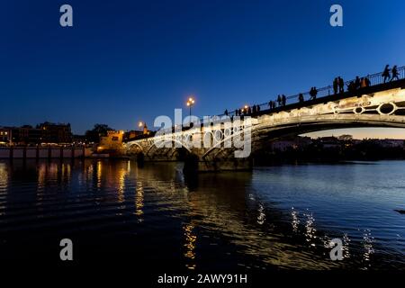 Ponte di Triana (Isabel II ponte) oltre il fiume Guadalquivir di notte, Siviglia, Spagna Foto Stock