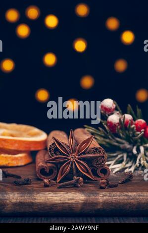 Spezie di Natale su tavola di legno con luci sfocate sullo sfondo Foto Stock