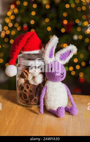 Il coniglio lavorato a maglia accanto al vaso decorativo con cappello di Natale dall'alto Foto Stock