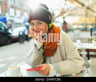 Ritratto sicuro giovane donna ascoltare musica con cuffie e lettore mp3 al caffè autunno marciapiede Foto Stock
