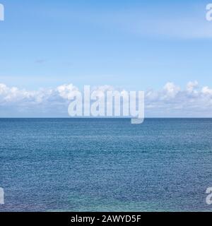 Nuvole che si formano in cielo blu su un orizzonte di mare Foto Stock