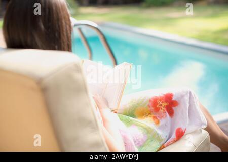 Donna rilassante, libro di lettura a bordo piscina estiva Foto Stock