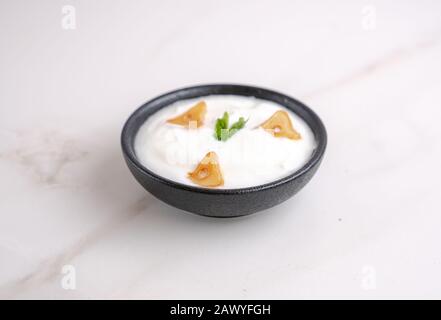 Salsa all'aglio in una ciotola su fondo bianco con qualche spicchio di aglio condito. Foto Stock