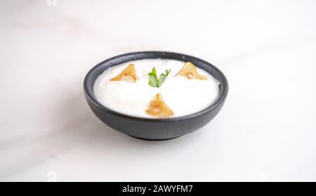 Salsa all'aglio in una ciotola su fondo bianco con qualche spicchio di aglio condito. Foto Stock