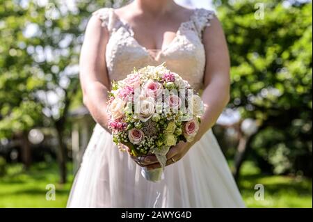 Bouquet di nozze di fiori tenuti dalla sposa closeup. Fiori rosa e giallo rose. Foto Stock