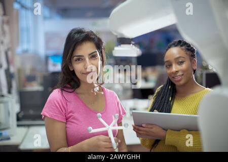 Ritratto sicuro ingegneri femminili con prototipo e braccio robotico in ufficio Foto Stock