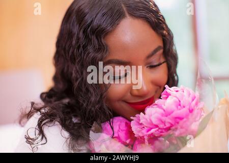 Chiudete la serena giovane donna che profumava freschi fiori di pony rosa Foto Stock
