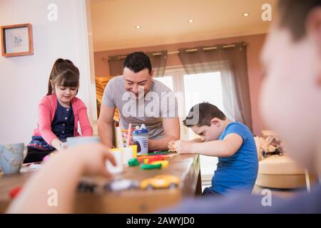 Buon padre che gioca con i bambini al tavolo da pranzo Foto Stock