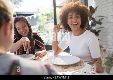 Felici giovani amici donne che si godono il pranzo al tavolo da pranzo Foto Stock