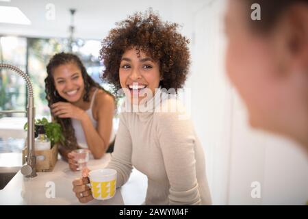Felici giovani amici donne ridere e bere tè in cucina Foto Stock