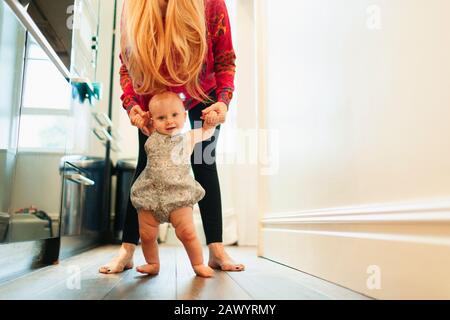 Ritratto madre aiutare bambino figlia camminare nel corridoio Foto Stock