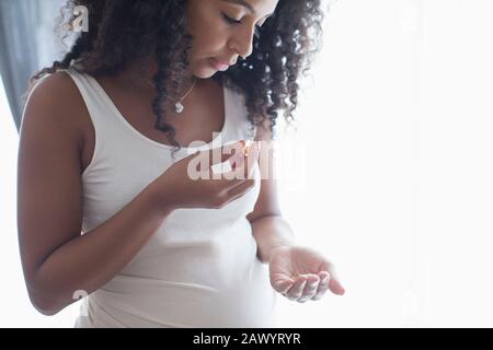 Giovane donna incinta che prende le vitamine Foto Stock