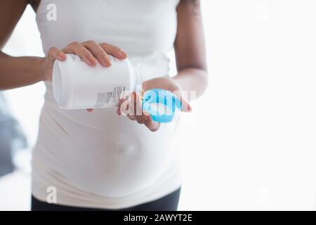 Giovane donna incinta che prende vitamine prenatali Foto Stock