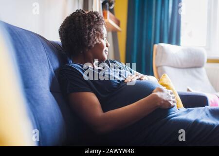 Serena donna incinta rilassante sul divano Foto Stock