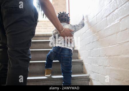 Padre aiutare bambino figlio salire le scale in scala Foto Stock