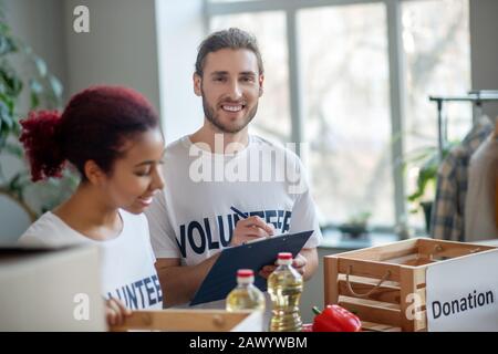 Giovane uomo con cartella e ragazza in magliette bianche. Foto Stock