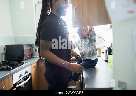 Padre e bambino figlio apertura armadio in appartamento cucina Foto Stock