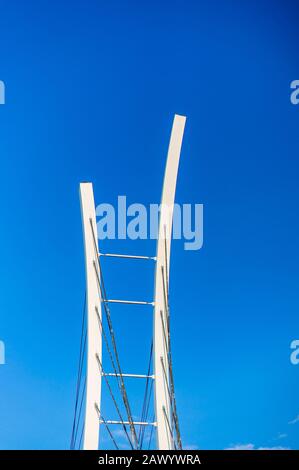 Immagine verticale di una scala metallica bianca sulla parte superiore di un edificio con cielo blu sullo sfondo Foto Stock