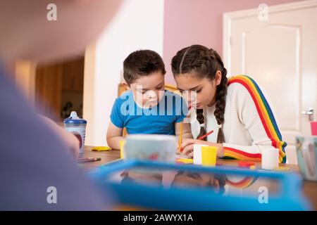 Ragazzo con sindrome Di Down e colorazione sorella a tavola Foto Stock