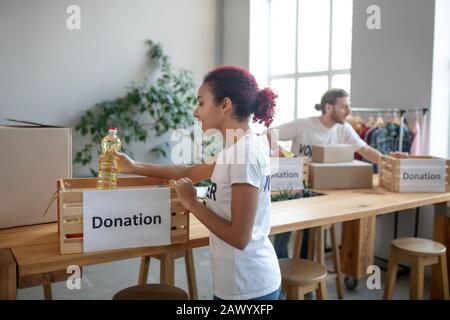 Giovane ragazza in Camicia bianca con bottiglia di olio vegetale. Foto Stock