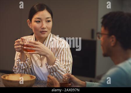 Ritratto di coppia etnica giovane godendo bevande mentre chattate al tavolo in caffetteria Foto Stock