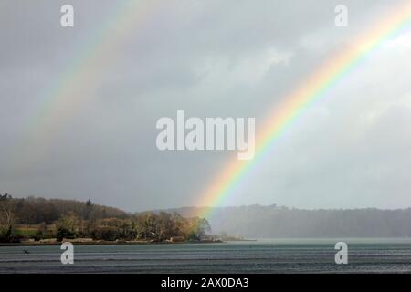 Double Rainbow sopra lo stretto di Menai guardando verso Anglesey. Vista Dalla Riserva Naturale Spinnies Aberogwen, Galles Del Nord Foto Stock